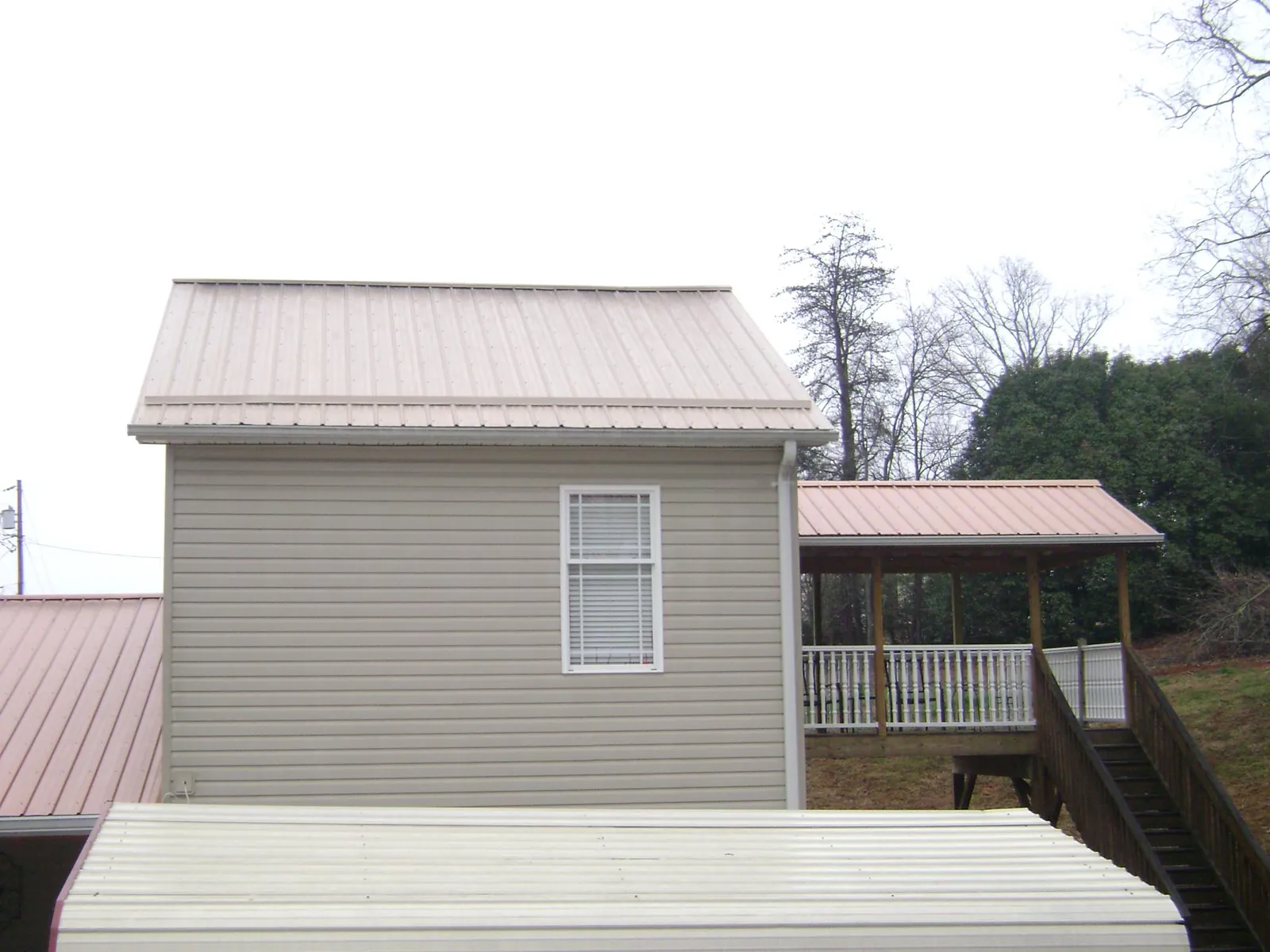 Tan metal roofs on a two story addition and attached porch, from a Roof Replacement job in Woodbine