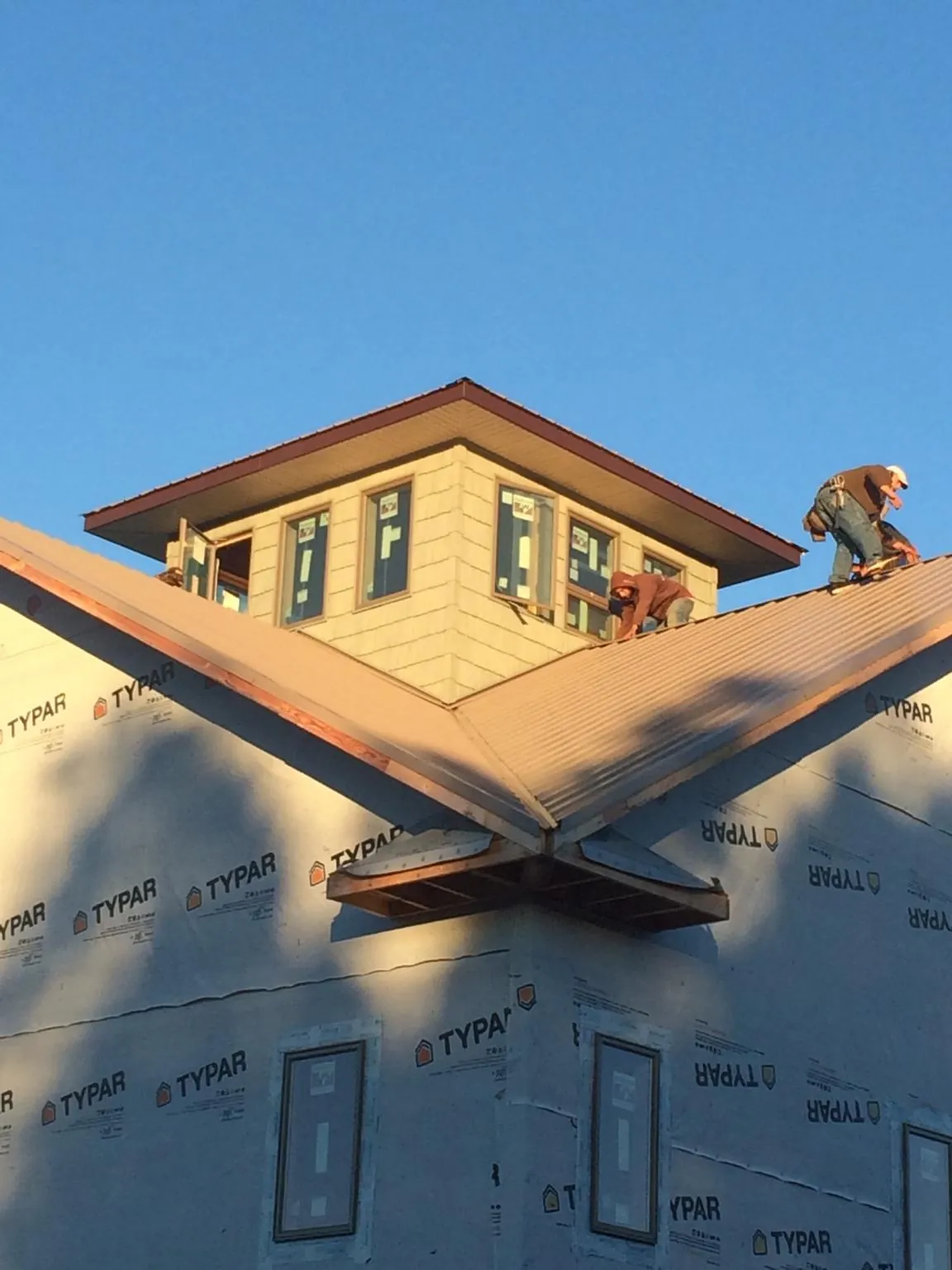 Roofers working around a rooftop cupola on a new metal roof at sunset — Roof Waterproofing in Woodbine by Roofing Brothers